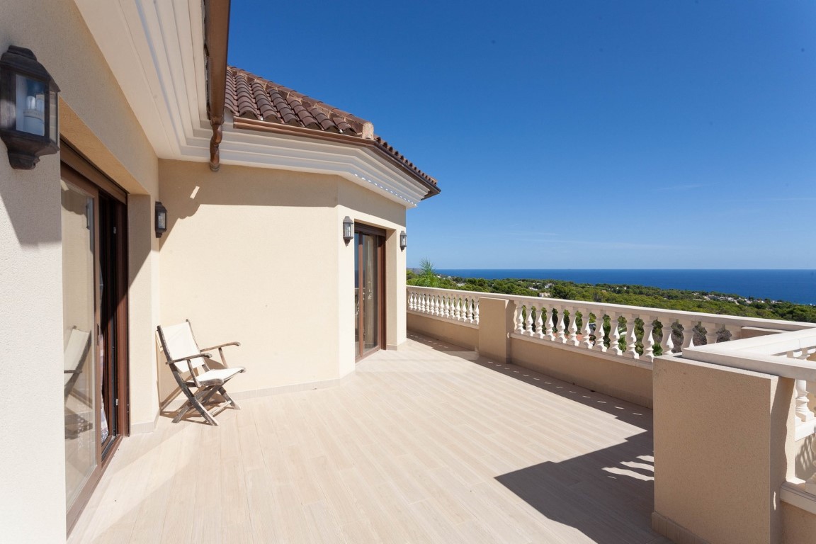 Spacious upper-floor balcony featuring a classic white balustrade, light tiled flooring, and panoramic views of the Mediterranean Sea and surrounding landscape.