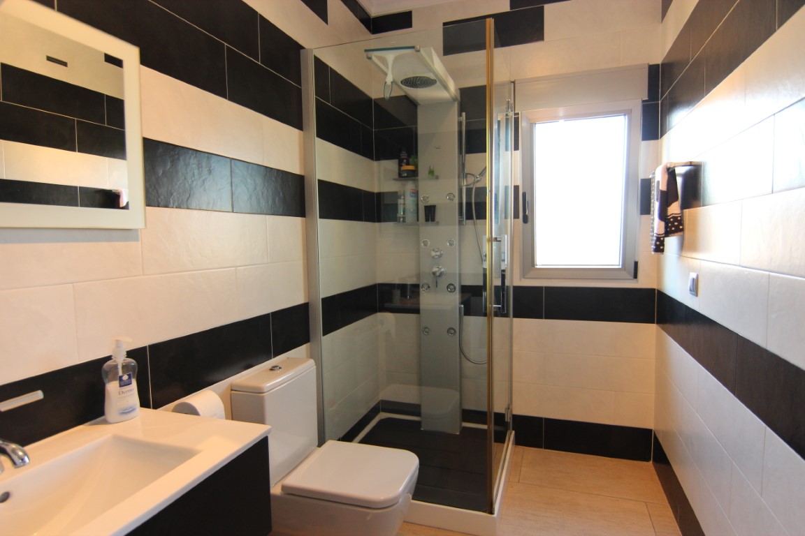 Contemporary bathroom with black and white horizontal tiles, featuring a glass shower enclosure with hydromassage column and natural light.