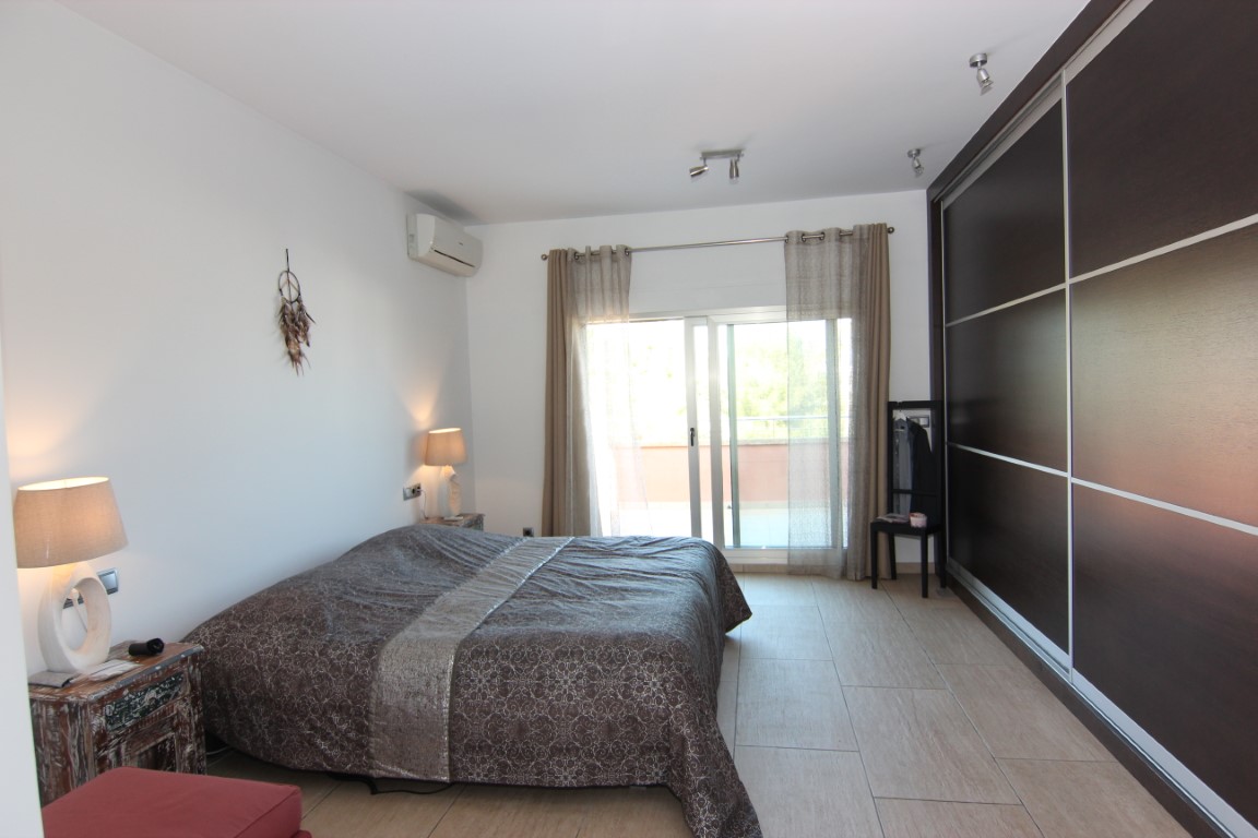 Double bedroom featuring a large dark wood sliding wardrobe, direct terrace access through glass doors, and integrated air conditioning.
