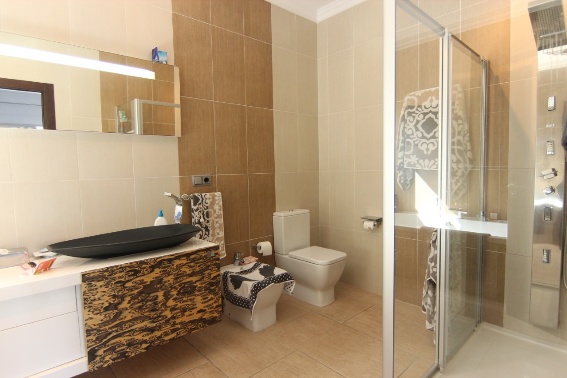 Modern bathroom featuring a black vessel sink, textured floating vanity, and a glass-enclosed shower with a multi-jet hydromassage panel.