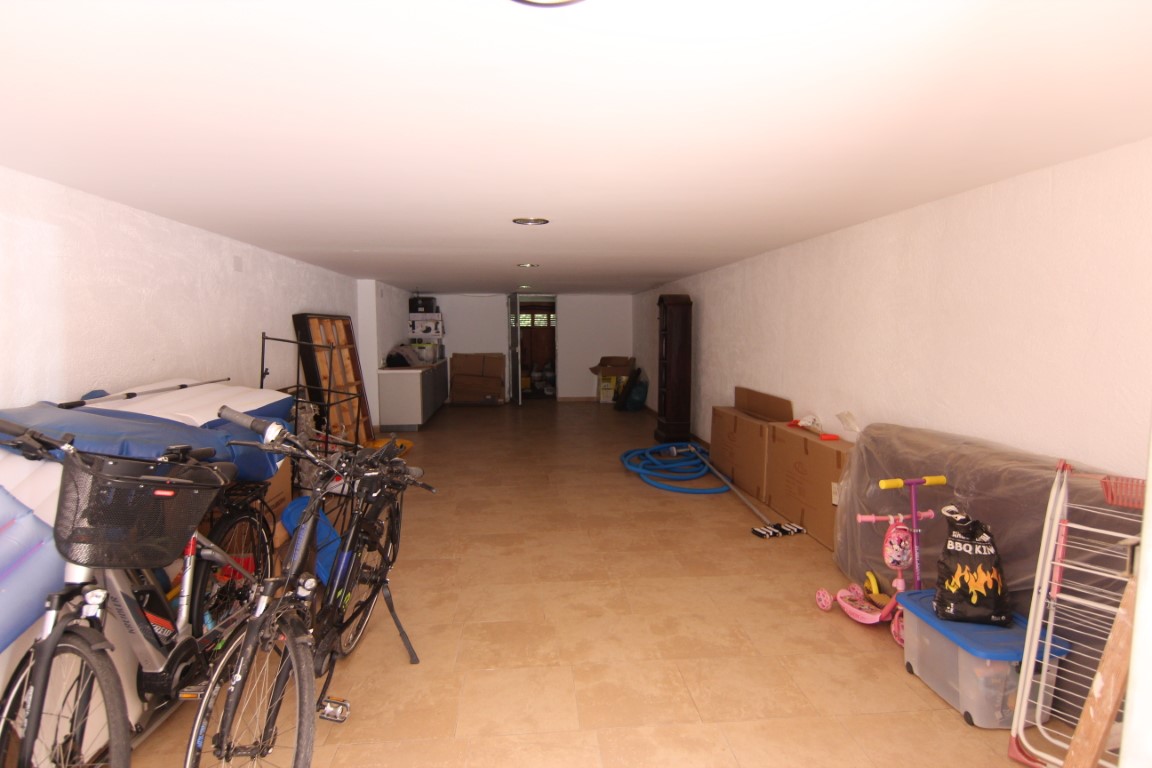 Spacious 60m2 garage featuring tiled flooring, white walls, and recessed ceiling lighting, providing ample storage and parking capacity.