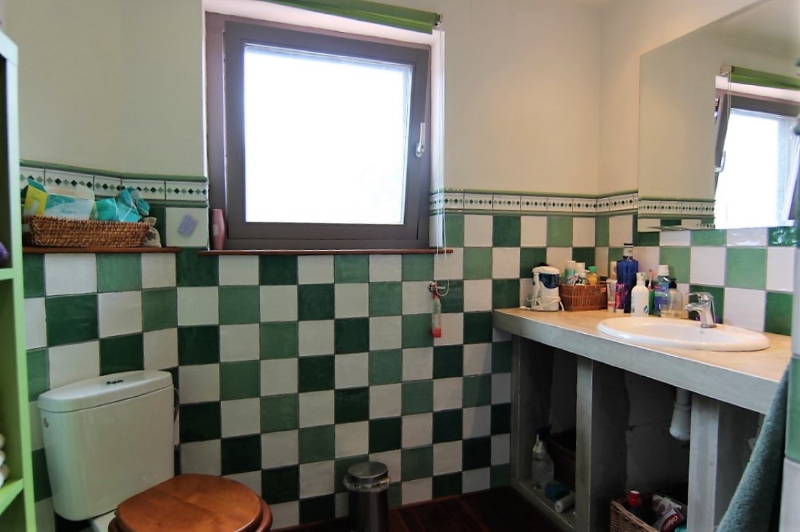 Bathroom featuring green and white checkered tiling, a built-in vanity with a white sink, and a window providing natural light.