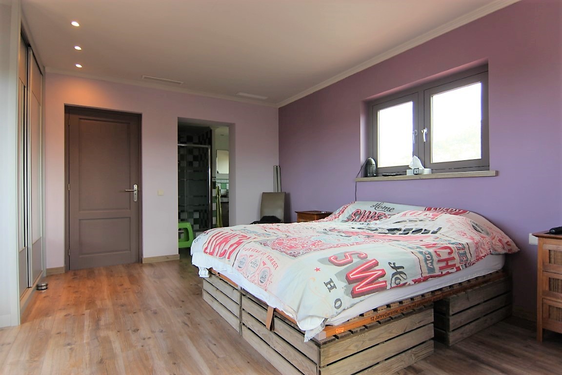Double bedroom featuring lilac walls, wooden flooring, and a creative pallet bed base. Includes recessed ceiling lights, built-in wardrobes, and an ensuite.