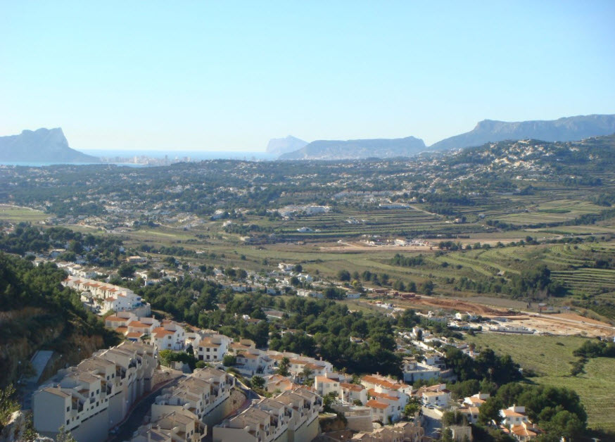 Panoramic elevated view overlooking the Benitachell valley towards the Mediterranean Sea, featuring terraced landscapes and distant views of the Peñón de Ifach.