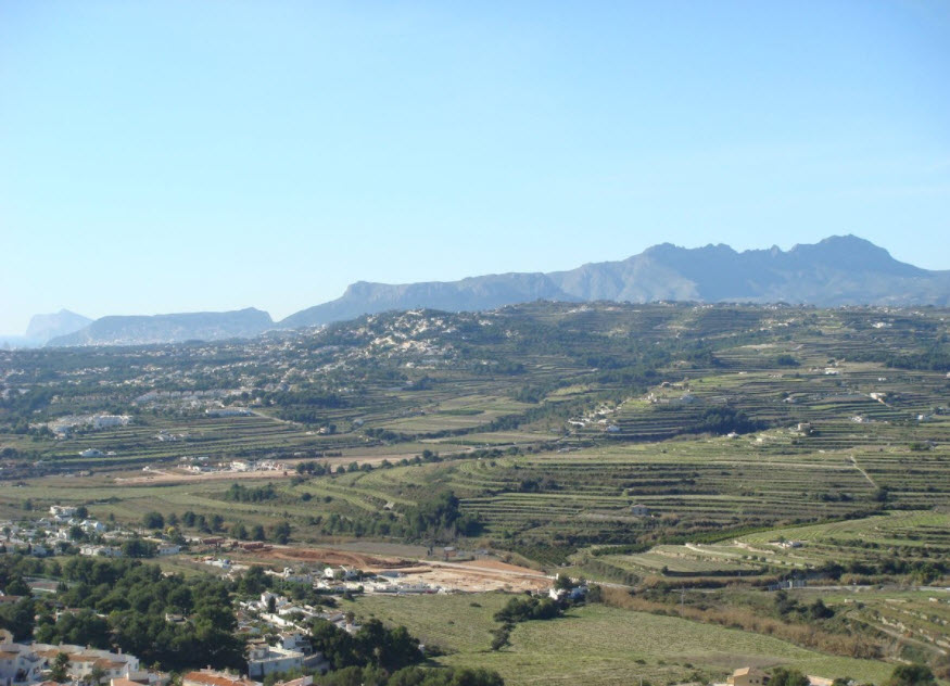 Panoramic view of the agricultural terraces and mountain ranges in Benitachell, showcasing the natural landscape and open surroundings.