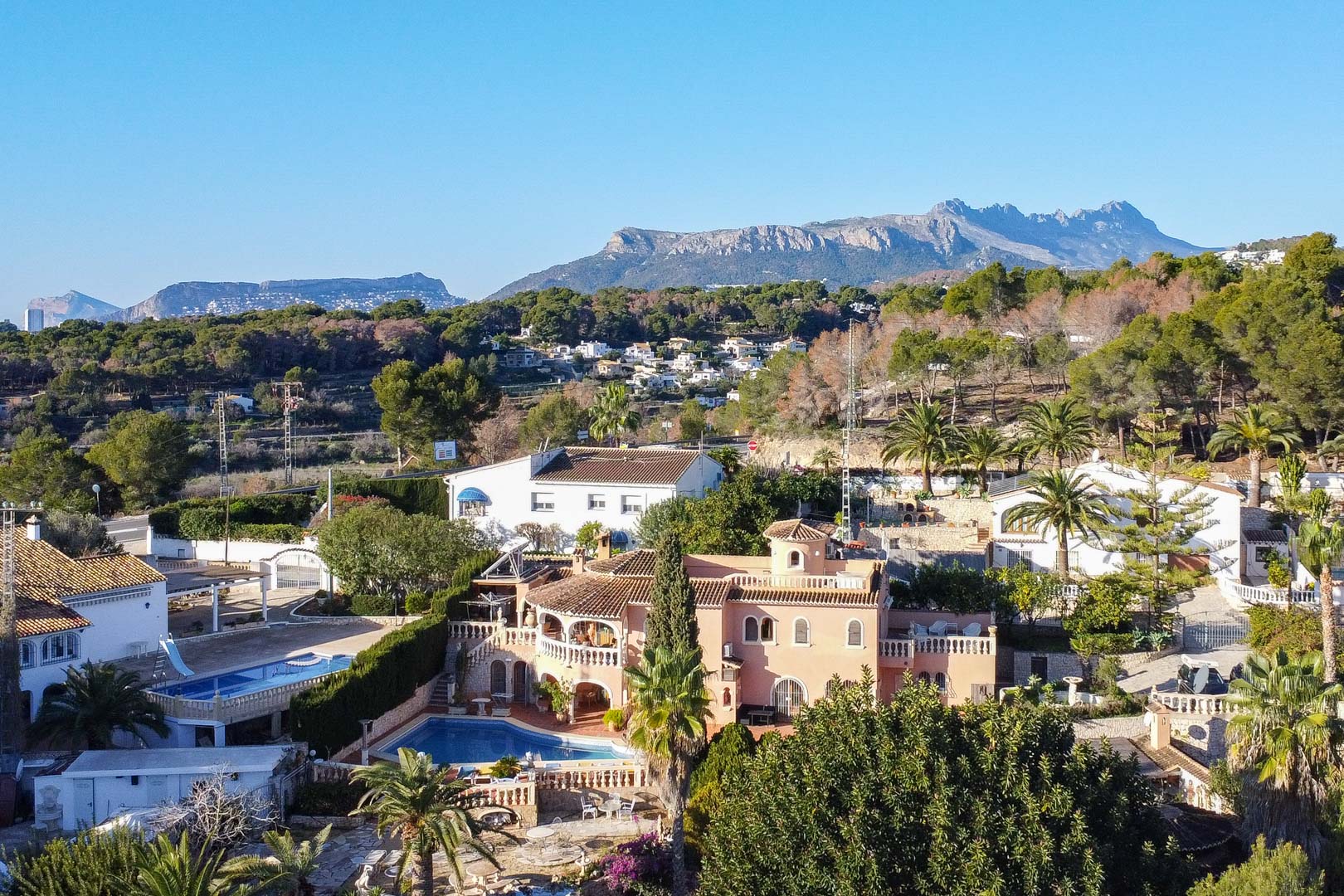 Elevated view of the Mediterranean villa featuring a private swimming pool and multi-level terraces, set against a backdrop of scenic mountain ranges.