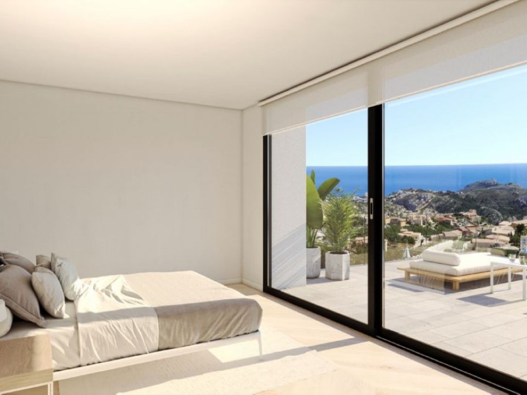 Modern bedroom featuring floor-to-ceiling sliding glass doors that open onto a private terrace with panoramic Mediterranean Sea views.