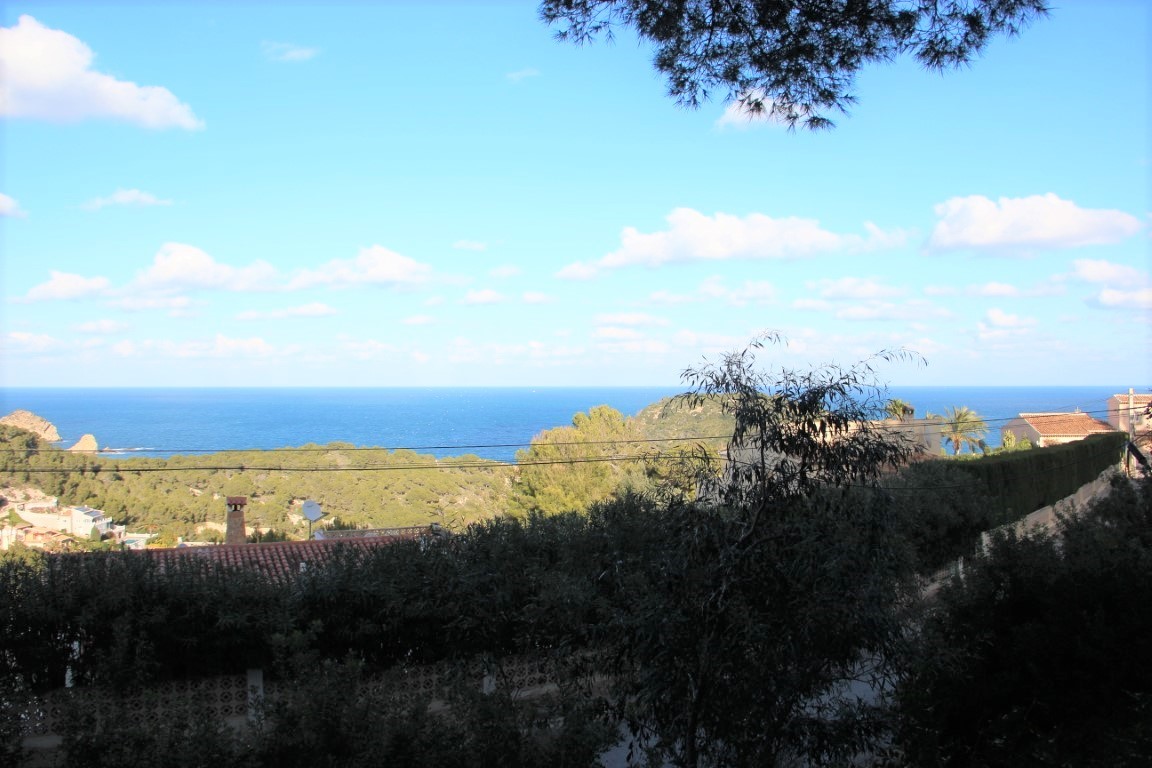 Panoramic Mediterranean Sea views from the plot, framed by native pine trees and traditional terracotta rooftops in a quiet residential area.