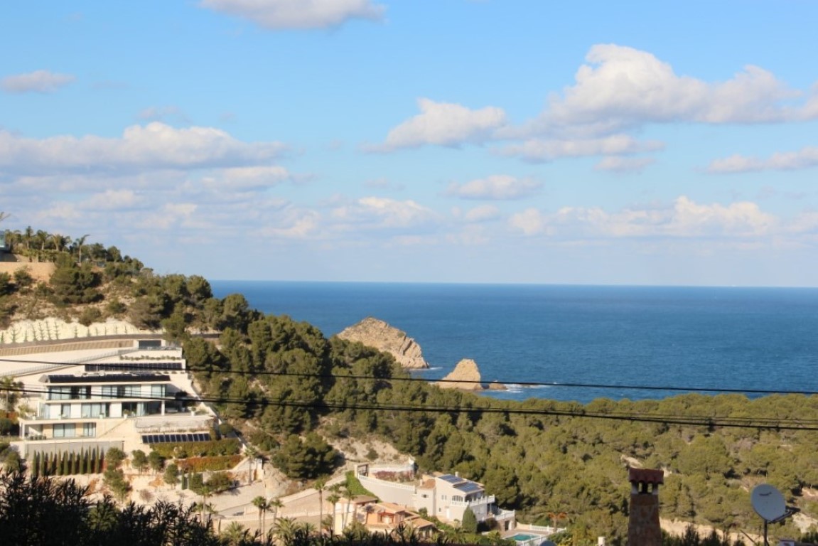 Panoramic view from the plot overlooking the Mediterranean Sea and Portichol Island, featuring modern villas nestled among the pine-covered hills of Jávea.