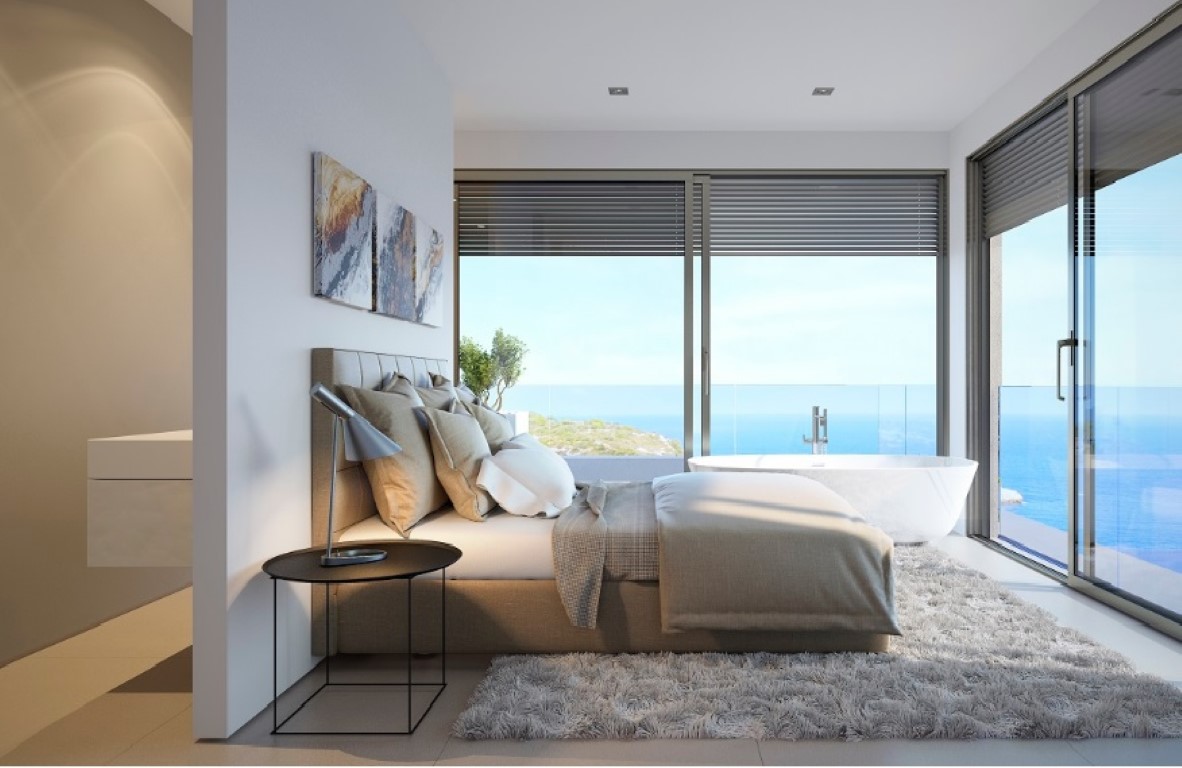 Master bedroom featuring a freestanding bathtub by floor-to-ceiling windows with panoramic sea views and minimalist interior design.