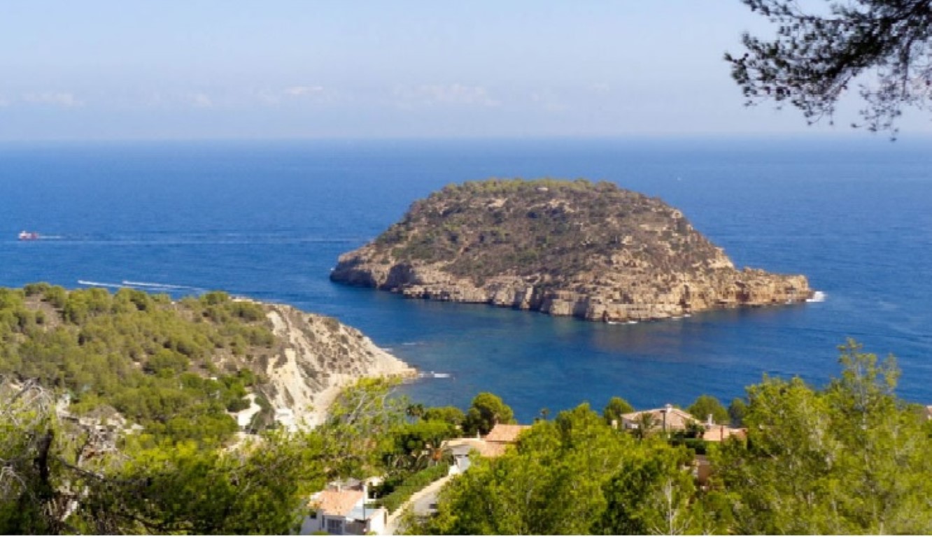 Panoramic views of the Mediterranean Sea and Portitxol Island, framed by native pine trees and coastal vegetation.