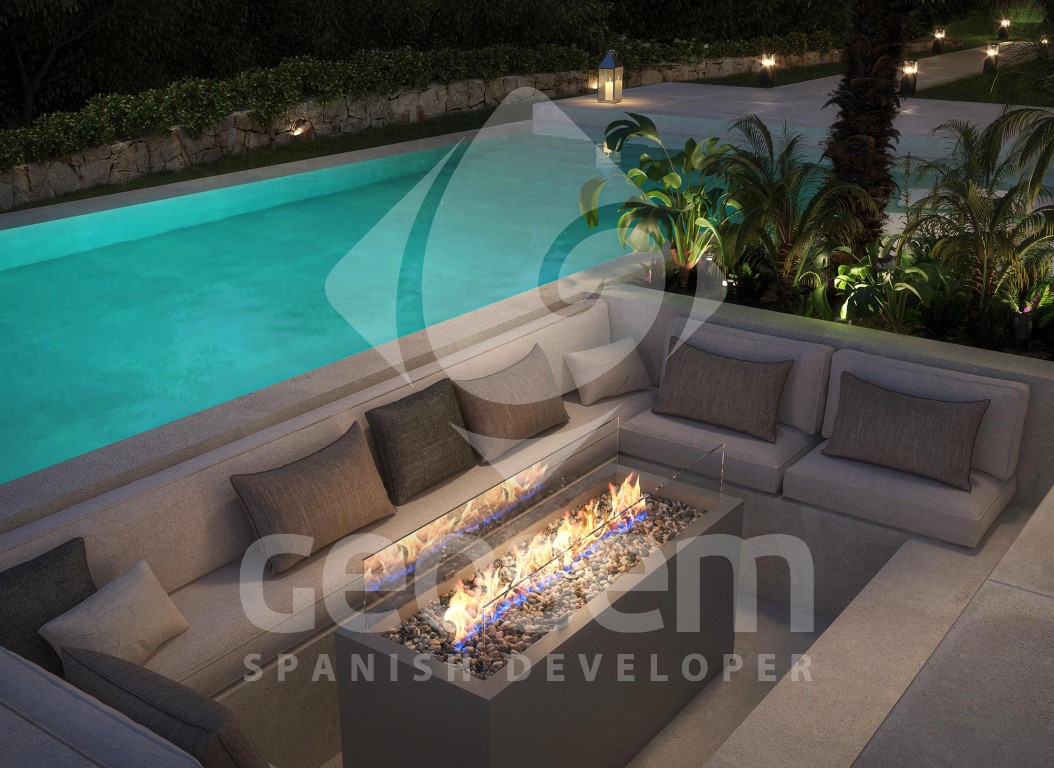 Sunken outdoor lounge area featuring a modern gas fire pit, grey cushioned seating, and an illuminated pool surrounded by Mediterranean landscaping.