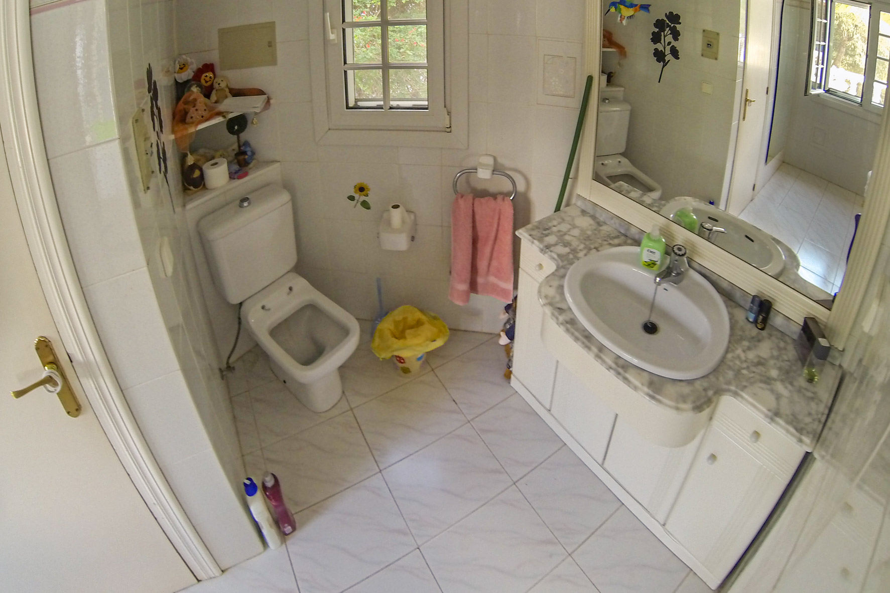 Bathroom featuring a marble-topped vanity, toilet, and white tile flooring.