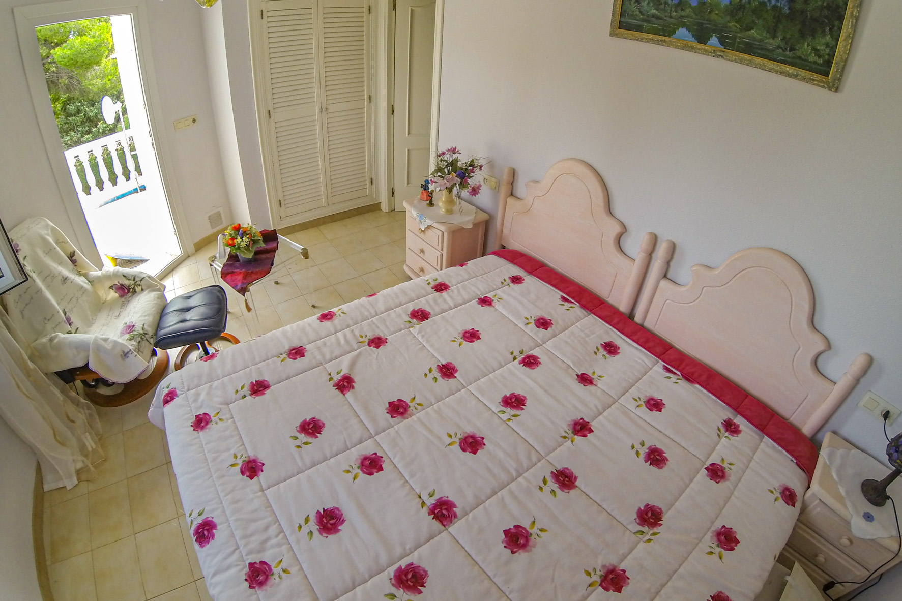 Bright bedroom features a double bed with floral bedding and terrace access.