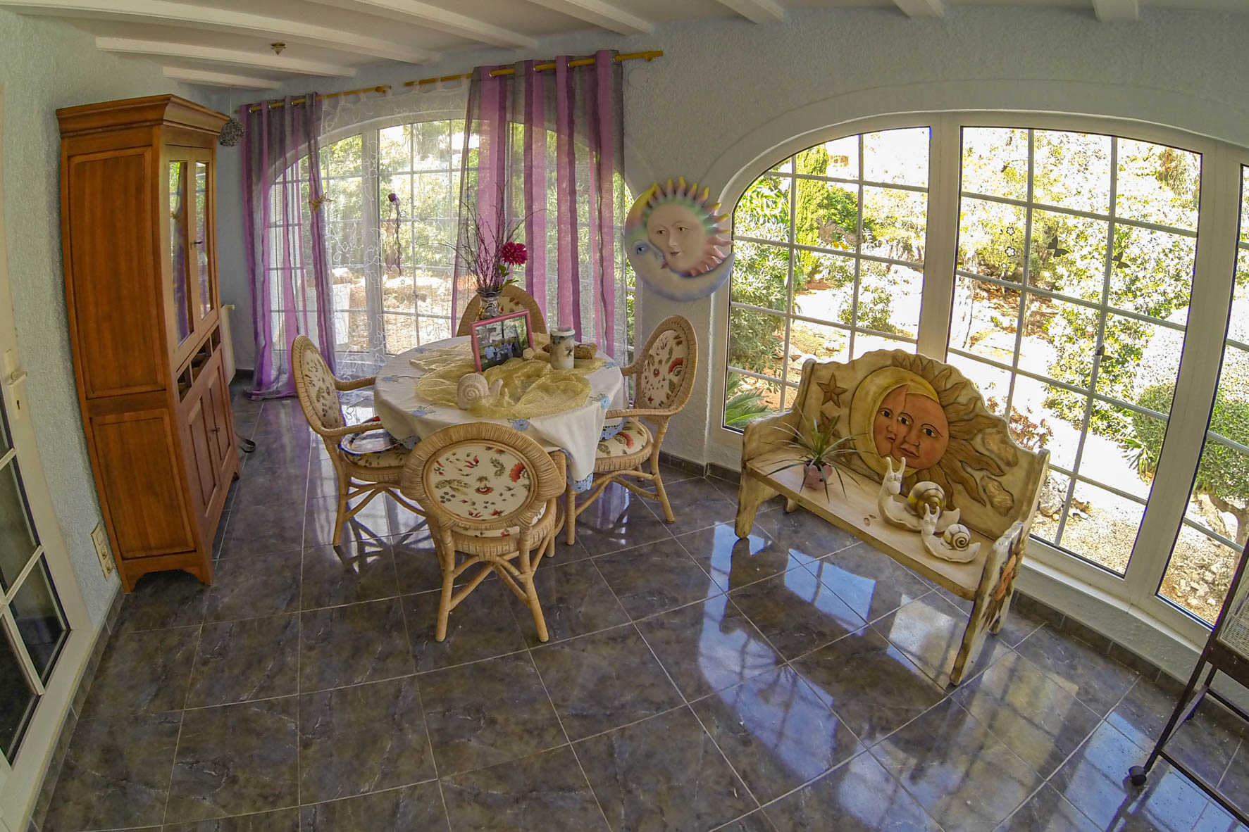 Bright dining area featuring a round table, wicker chairs, and sun and moon themed decor.