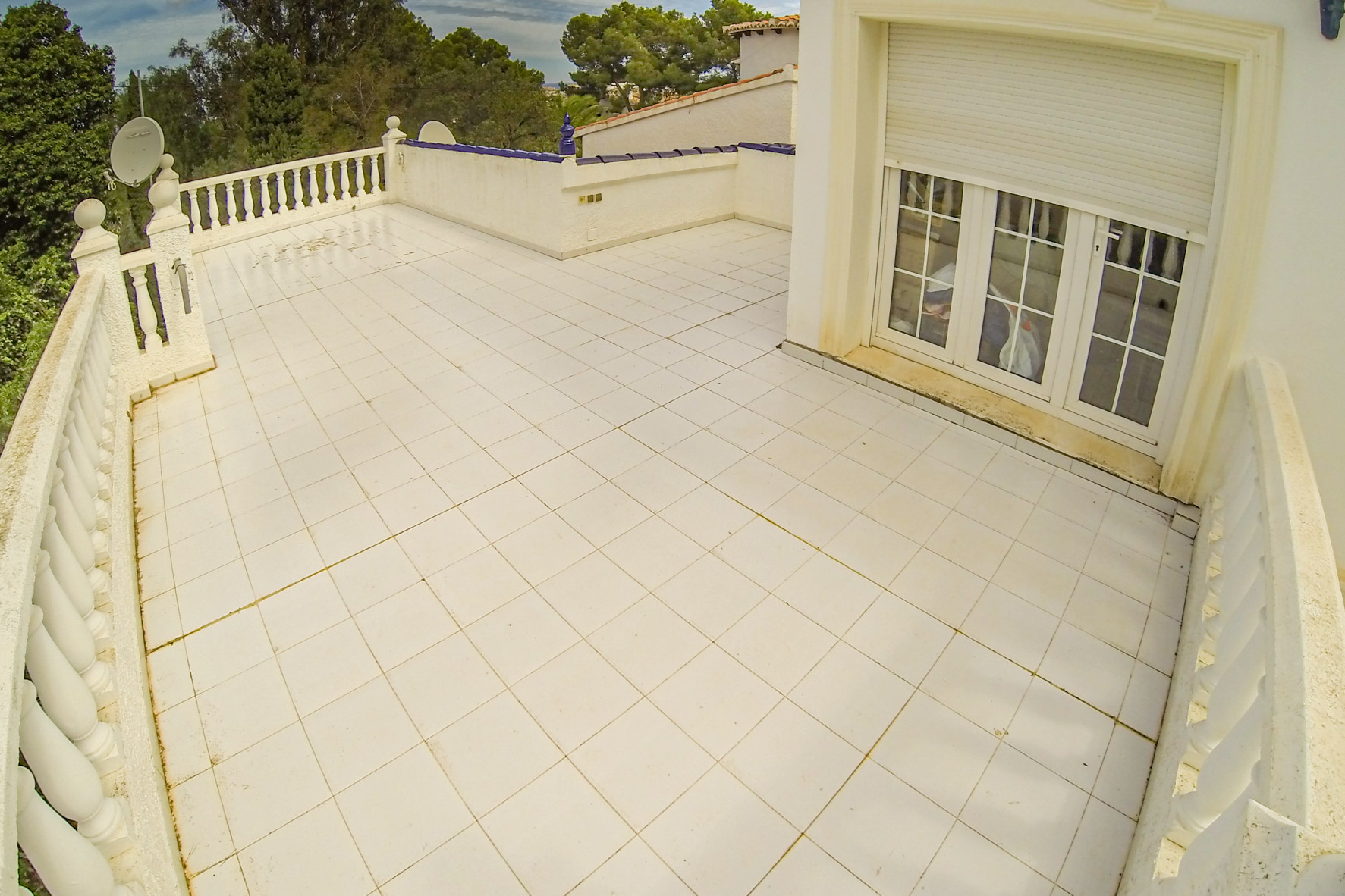 Expansive terrace with white tile flooring and balustrade railing, perfect for outdoor enjoyment.