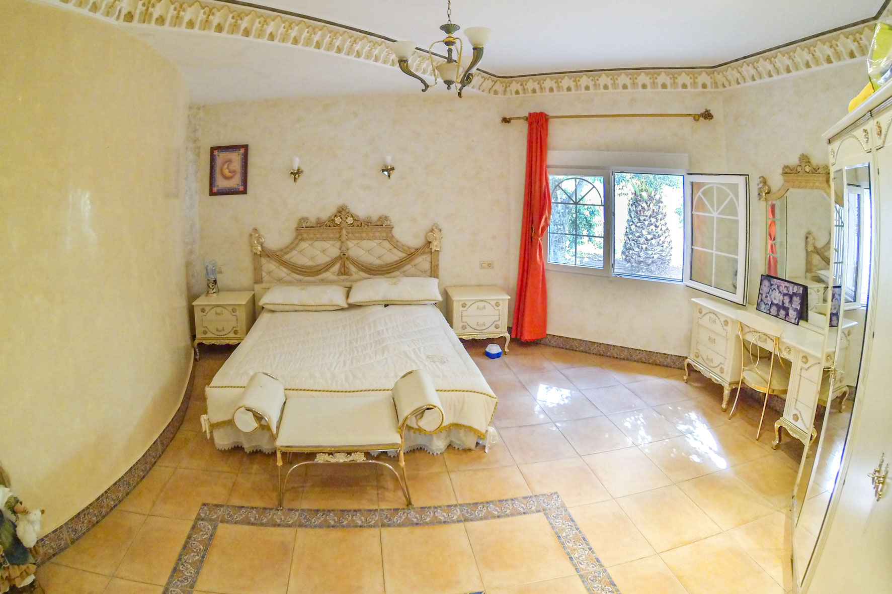 Furnished master bedroom featuring a double bed, vanity, and garden views through a window.