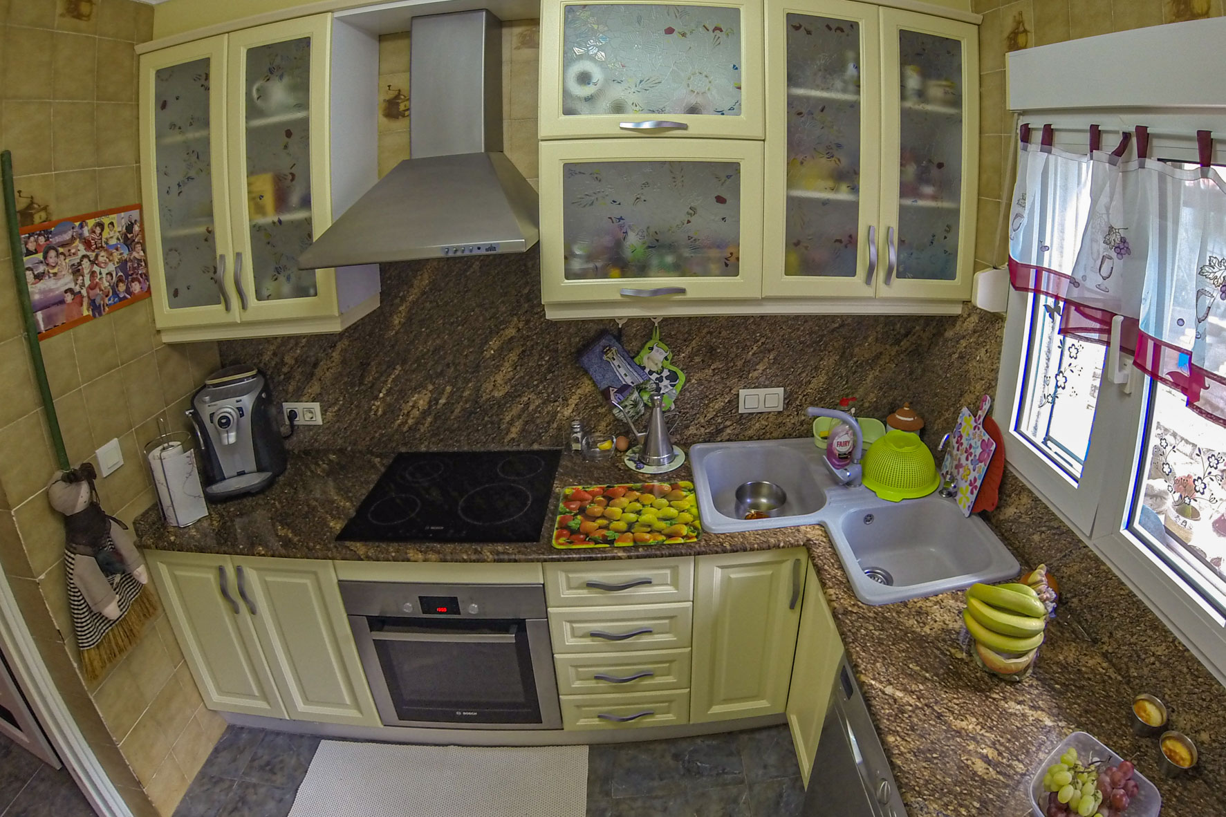 Kitchen view with brown granite countertop, modern appliances, and cream-colored cabinets.