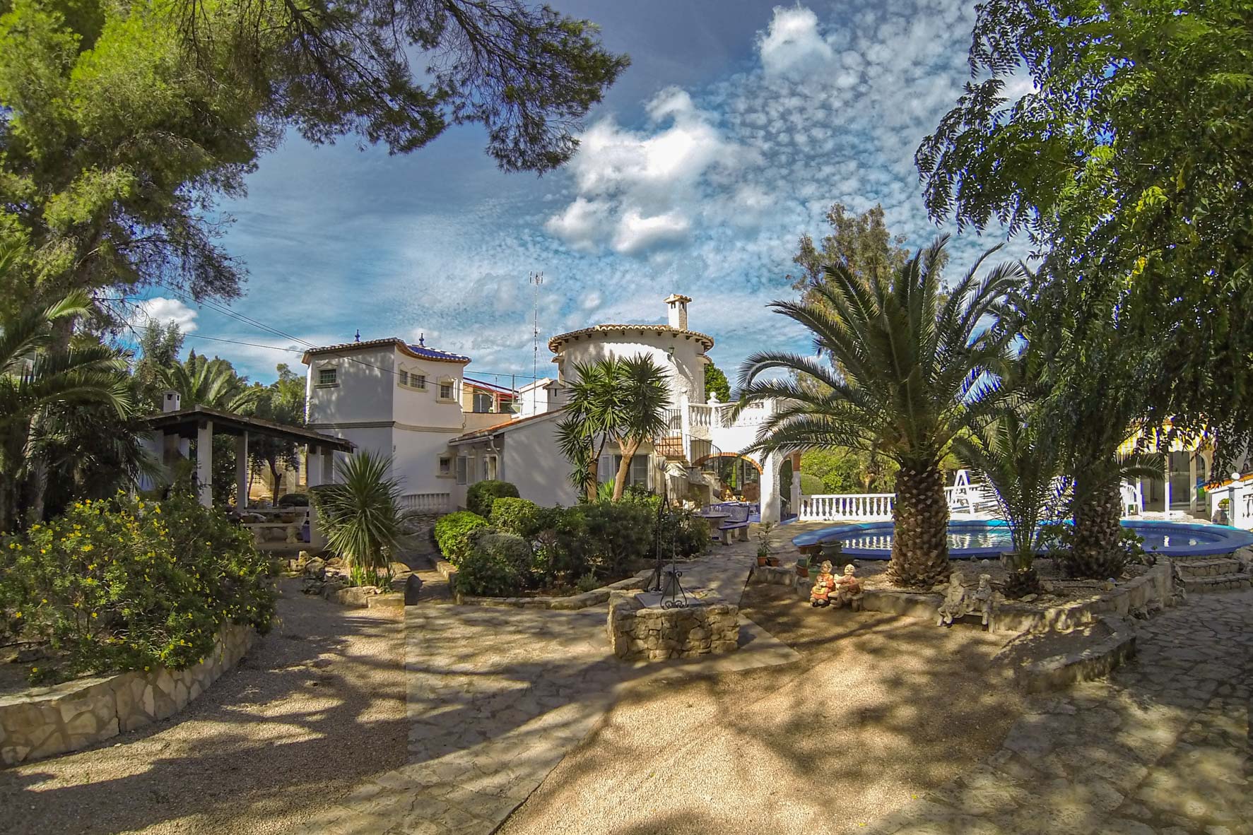 View of the mature garden featuring a circular pool and the Mediterranean-style main house.