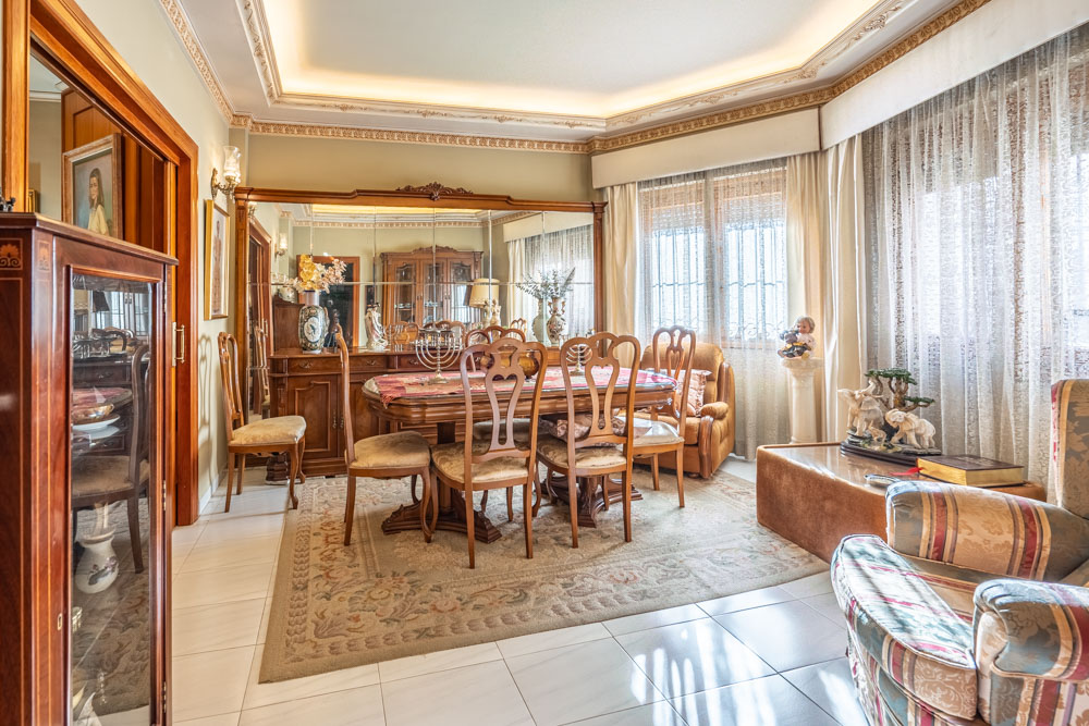 Formal dining room featuring classic wooden furniture, decorative ceiling moldings with recessed lighting, and a large mirrored sideboard that enhances the sense of space.