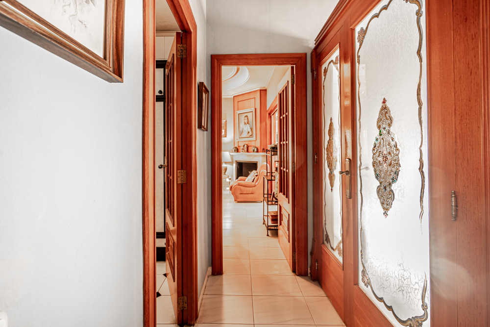Hallway featuring solid wood joinery and ornate etched glass doors, offering a direct view into the living area with its classic fireplace.