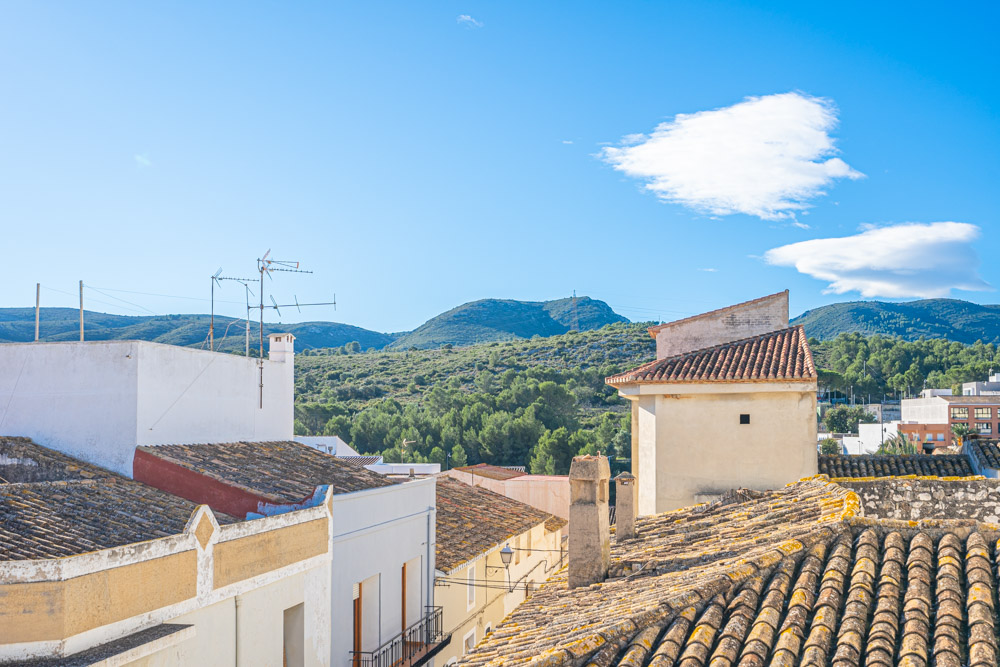 Panoramic view from the roof terrace overlooking the traditional tiled rooftops and the green mountains of the nearby nature reserve.