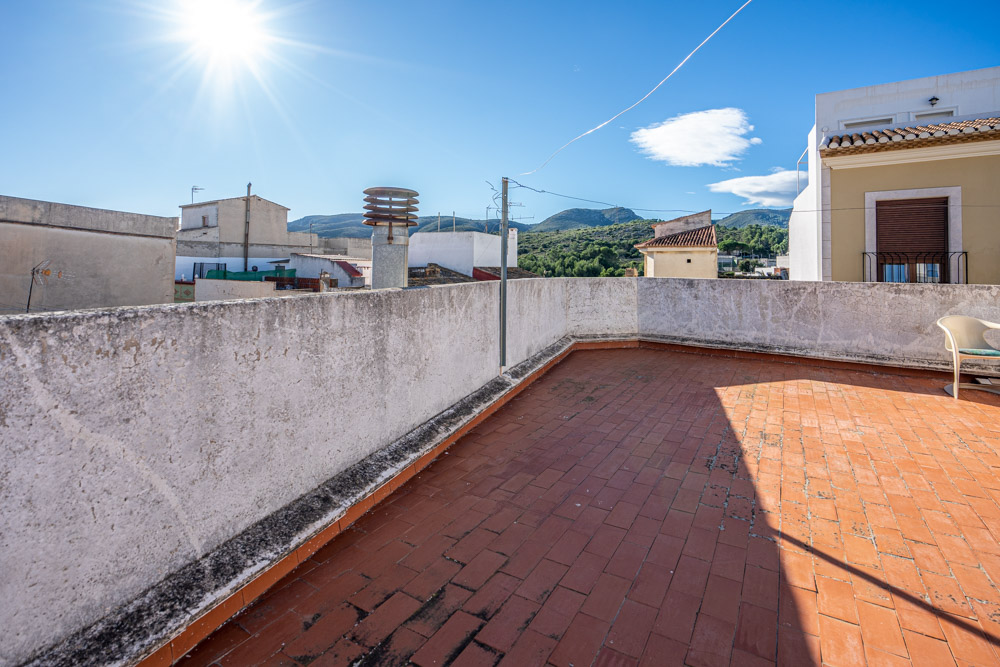 Rooftop terrace featuring traditional terracotta tiling and panoramic views of the surrounding mountains and village rooftops.