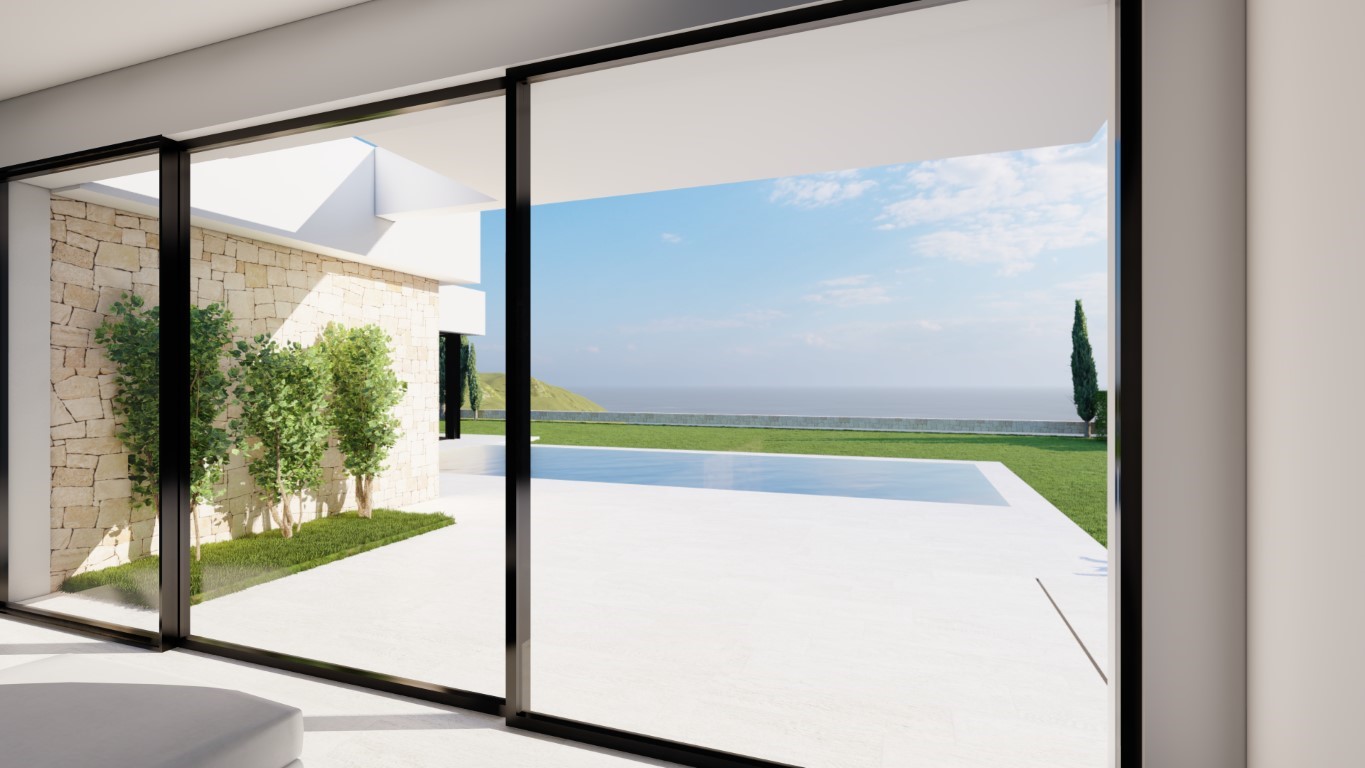 View through floor-to-ceiling sliding glass doors showcasing the white stone terrace, private pool, and expansive sea views beyond the lawn.