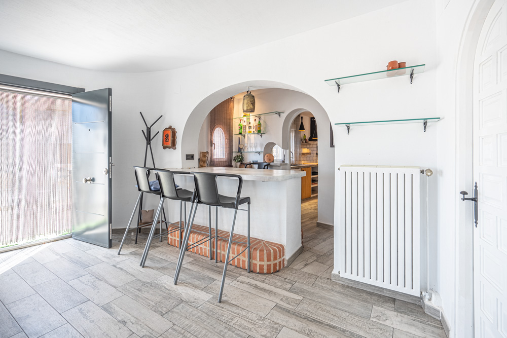 Entrance area featuring a breakfast bar with brick detailing, wood-effect tile flooring, and an arched opening leading to the kitchen.