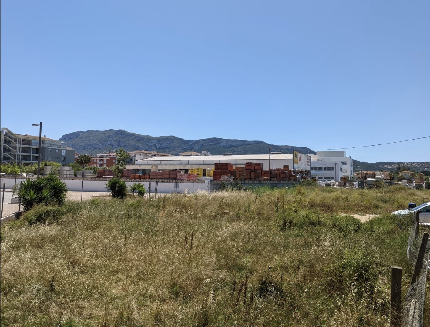 Level plot featuring natural vegetation and clear views of the Montgó mountain, located adjacent to established commercial and residential areas.