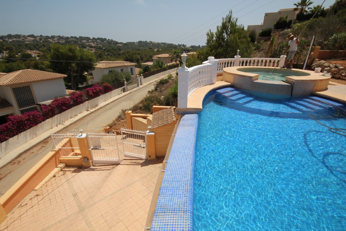 Elevated swimming pool with blue mosaic tiling and an integrated circular jacuzzi, featuring a white balustrade and panoramic views of the Javea valley.