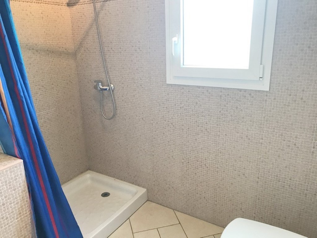Modern shower area featuring beige mosaic wall tiles, a white square shower tray, and a frosted window for natural light and privacy.