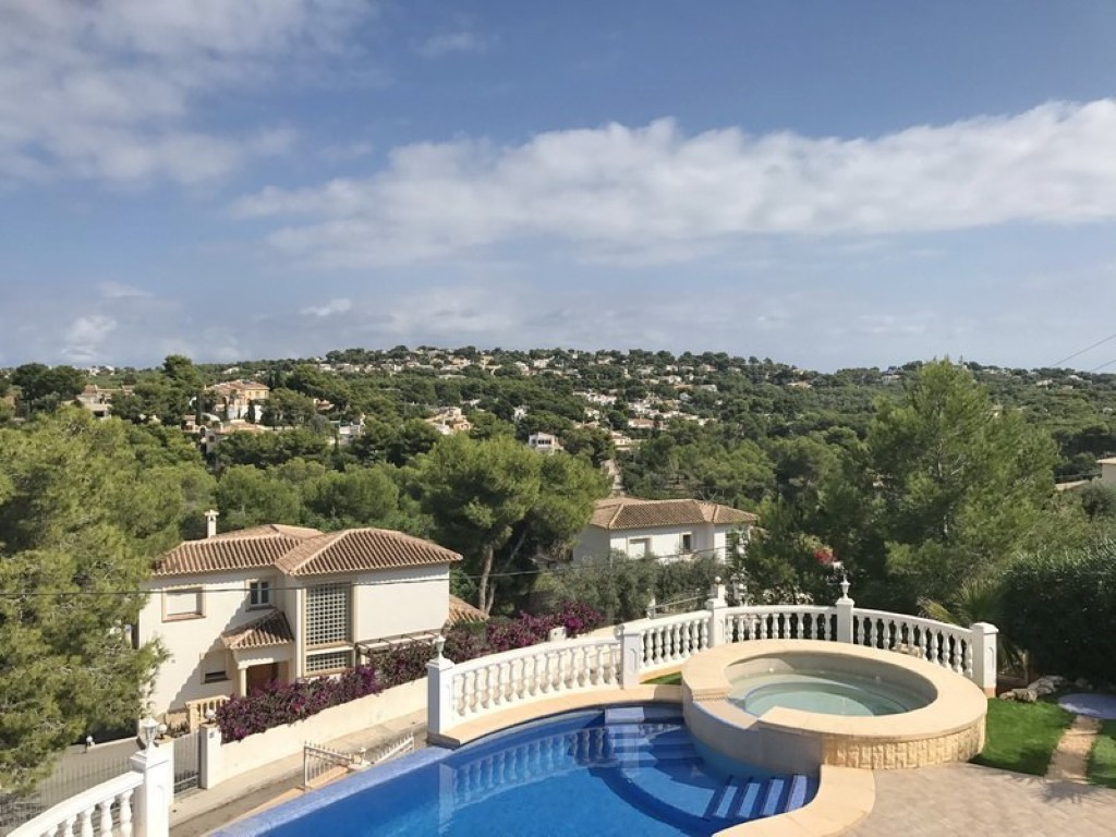Outdoor terrace featuring a curved swimming pool and integrated circular jacuzzi, offering panoramic views of the pine-covered valley and surrounding villas.