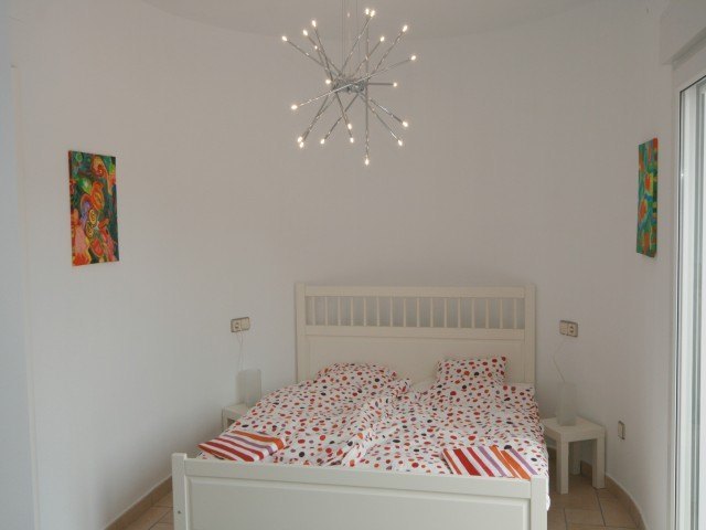 Bedroom featuring a white wooden bed frame, a contemporary starburst chandelier, and access to the outdoors via sliding glass doors.