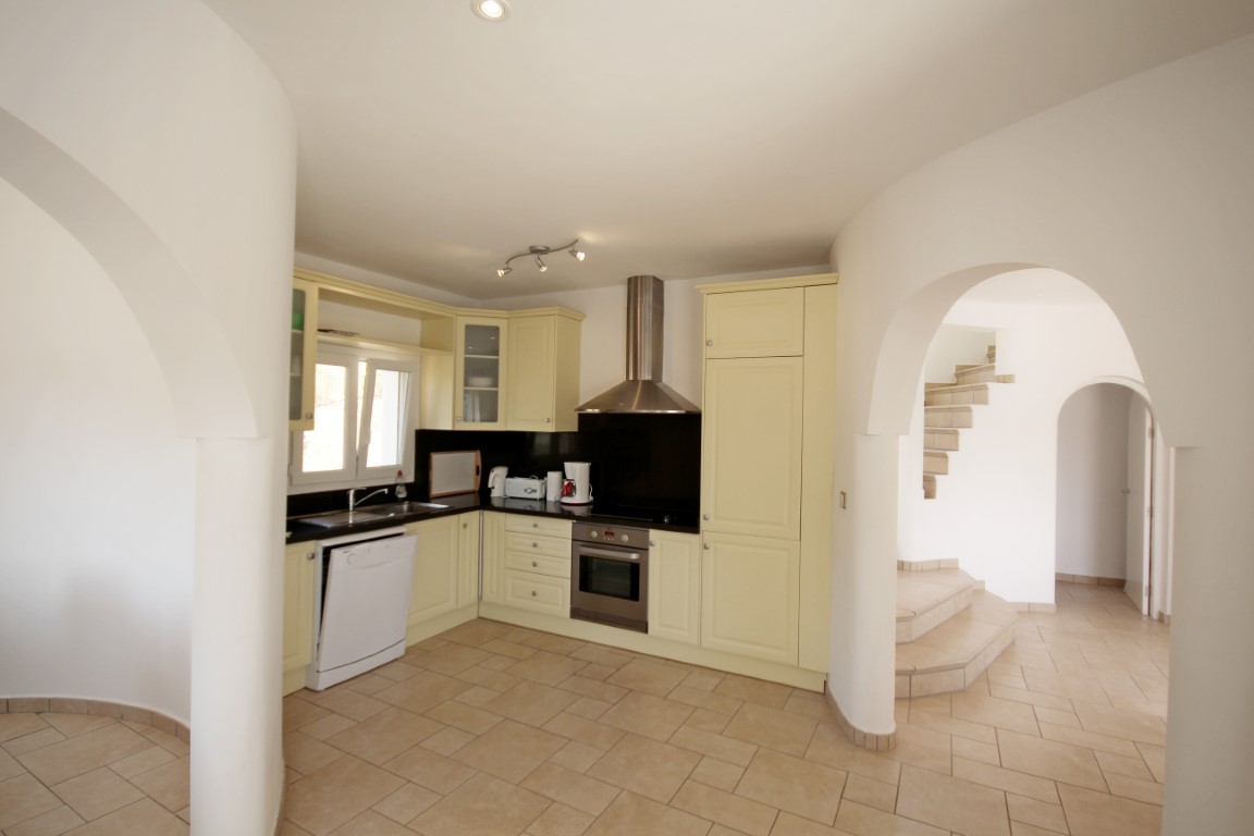 Fully equipped kitchen featuring cream cabinetry, black granite countertops, and stainless steel appliances, framed by Mediterranean-style arched doorways.