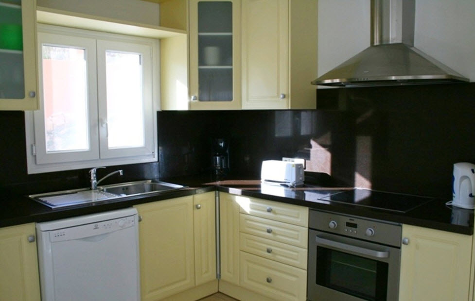 Fully equipped kitchen featuring dark granite countertops, cream-toned cabinetry, and integrated stainless steel appliances including an oven and extractor.