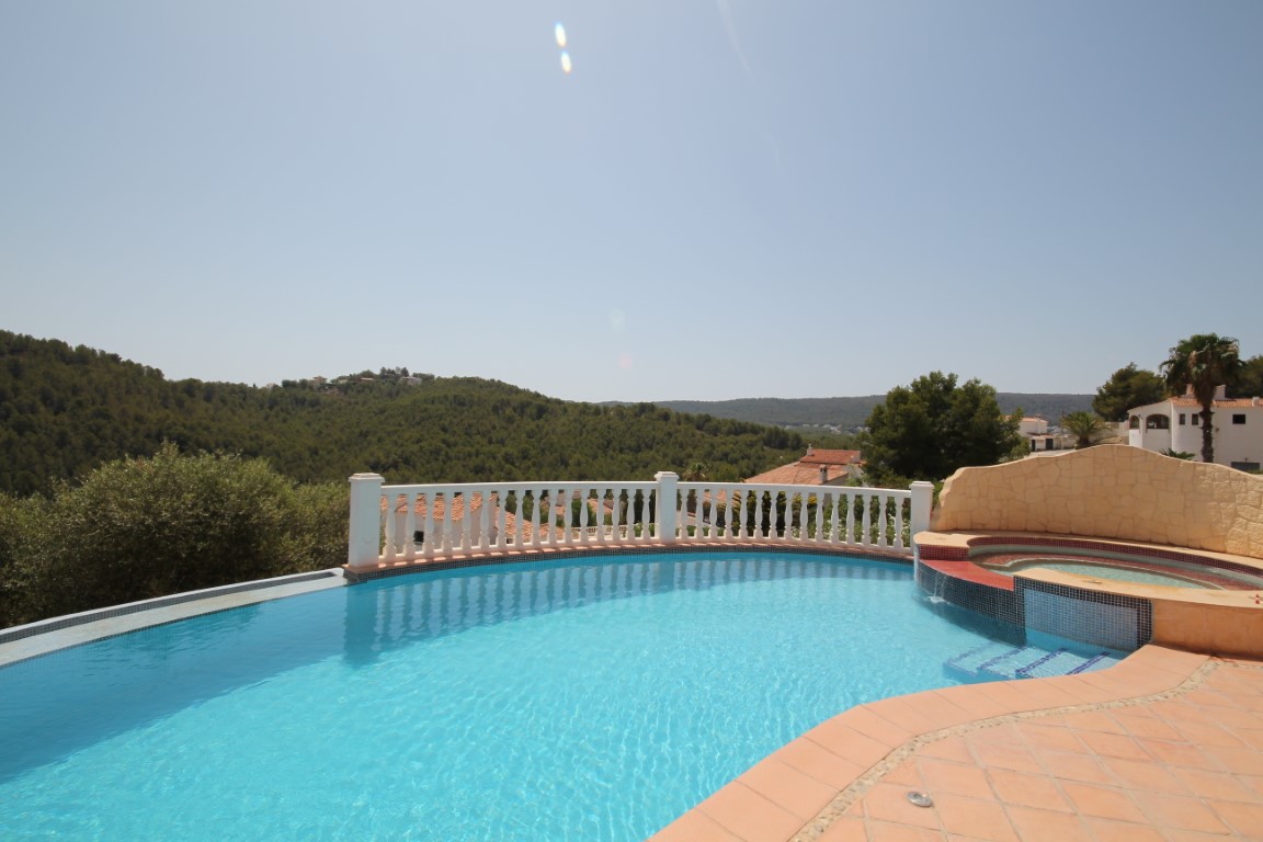 Sun terrace featuring a curved infinity pool, integrated circular jacuzzi, and panoramic views of the lush Mediterranean hills.