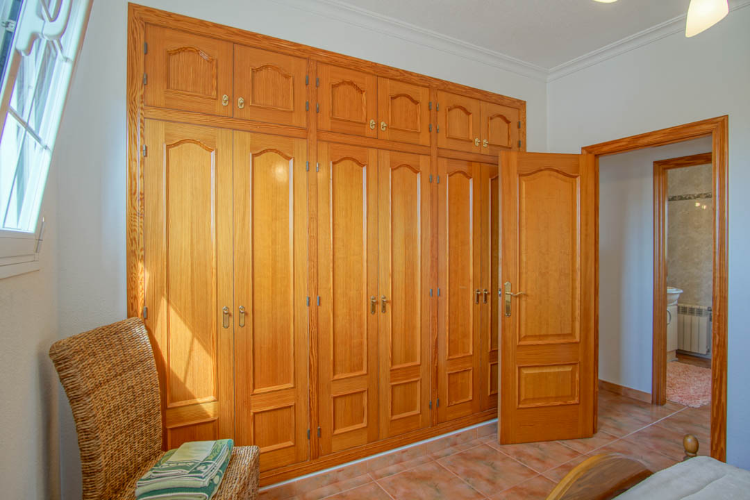 Bedroom featuring a large floor-to-ceiling solid wood built-in wardrobe and matching interior doors with traditional tiling.