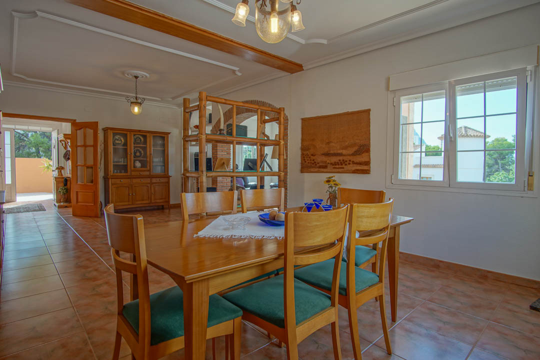 Dining area featuring a solid wood table, tiled flooring, and decorative ceiling moldings. A bamboo room divider separates the space from an arched brick entryway.