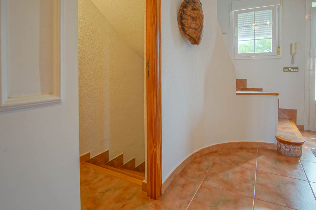 Entrance hallway featuring ceramic tile flooring and solid wood frames, linking the villa's floors through a central internal staircase.