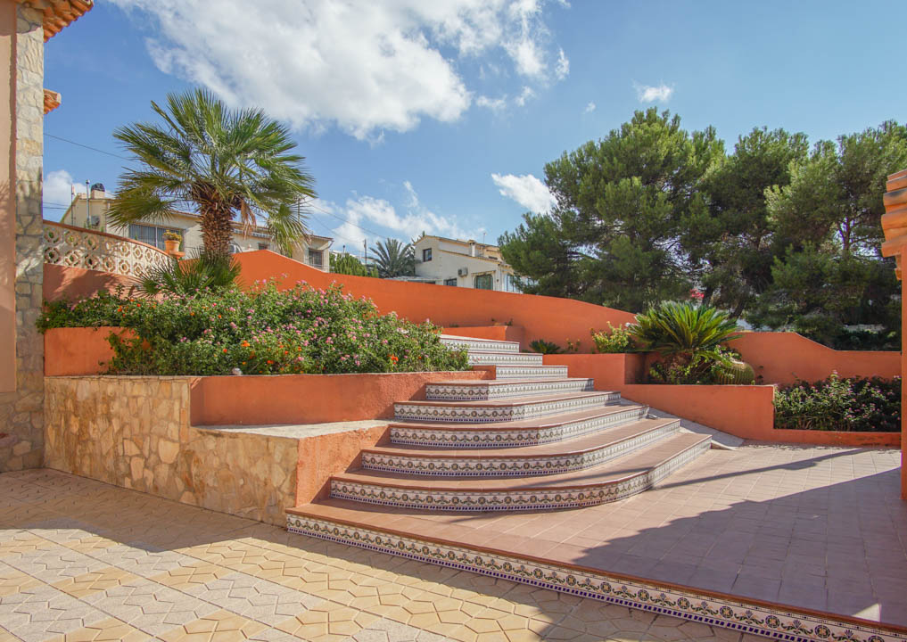 Outdoor staircase featuring decorative ceramic tile risers and terracotta walls, integrated with stone masonry and Mediterranean landscaping.