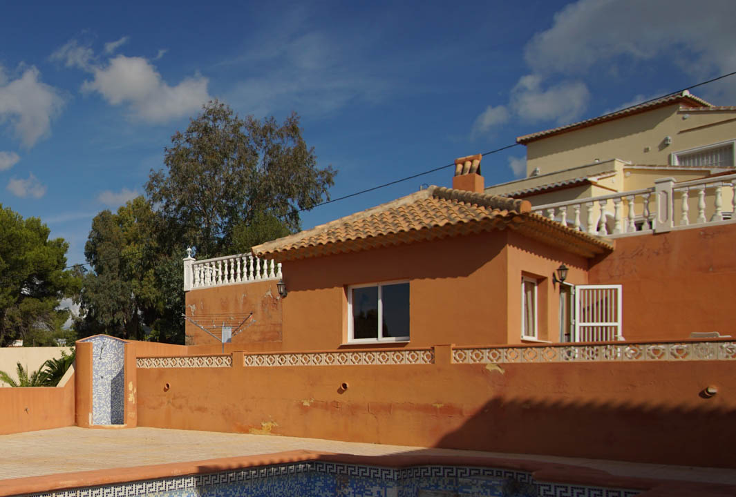 Pool area featuring a blue mosaic outdoor shower and a separate annex with a traditional terracotta tile roof and warm-toned walls.