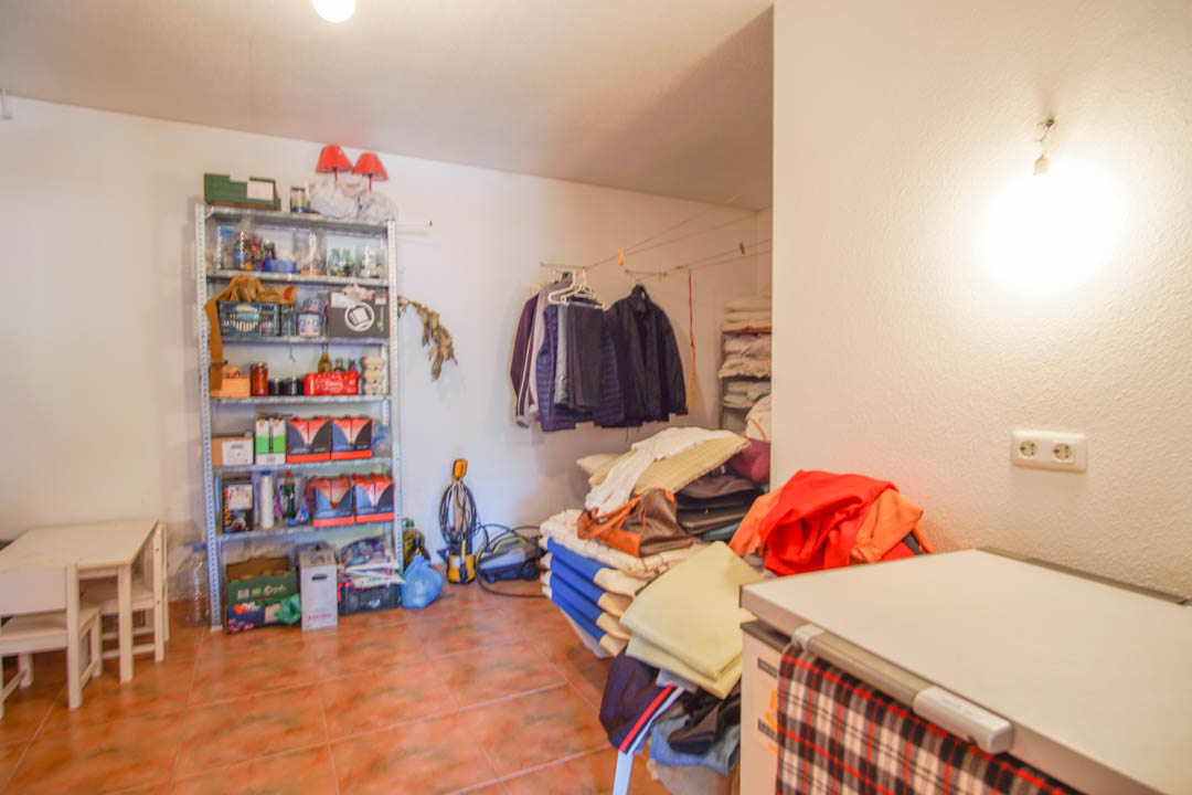 Spacious ground-floor storage room featuring ceramic tile flooring, metal shelving units, and a functional layout for laundry and organization.