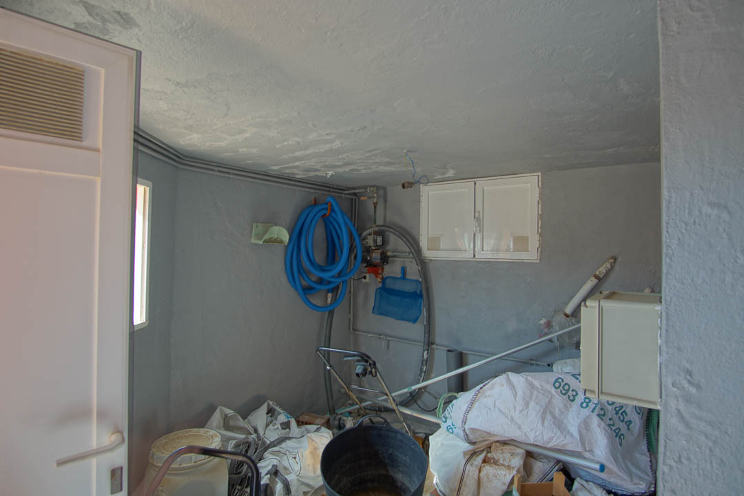 Utility and storage room featuring grey textured walls, organized pool maintenance equipment, and integrated technical installations for the villa.