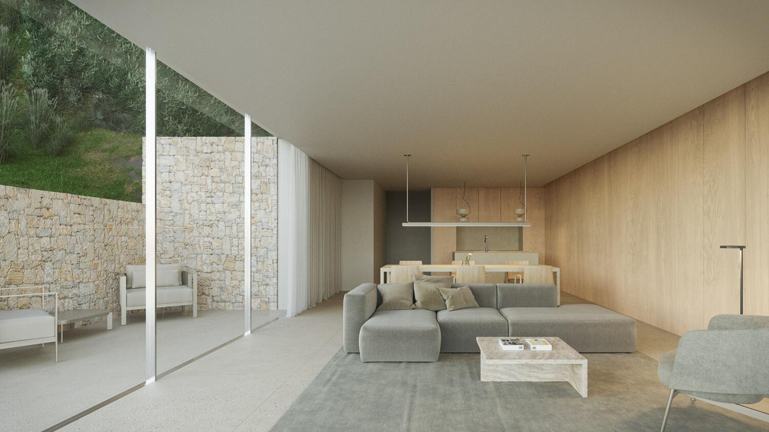 Open-plan living area featuring a grey sectional sofa, light wood wall paneling, and floor-to-ceiling glass doors opening to a stone-walled patio.