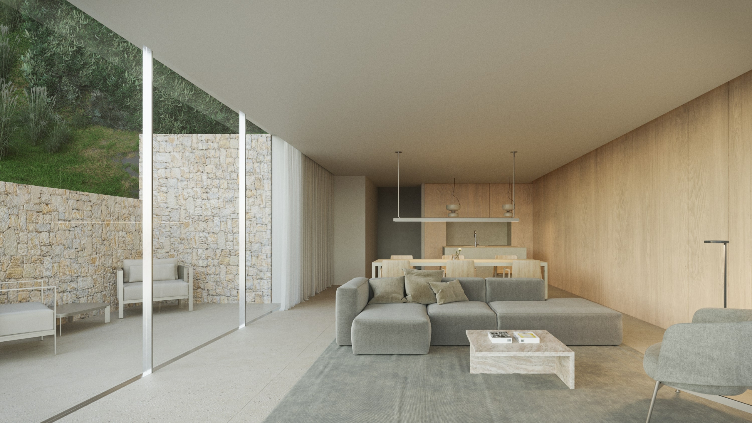 Open-plan living area featuring grey sectional seating, warm wood paneling, and floor-to-ceiling glass doors opening to a stone-walled terrace.