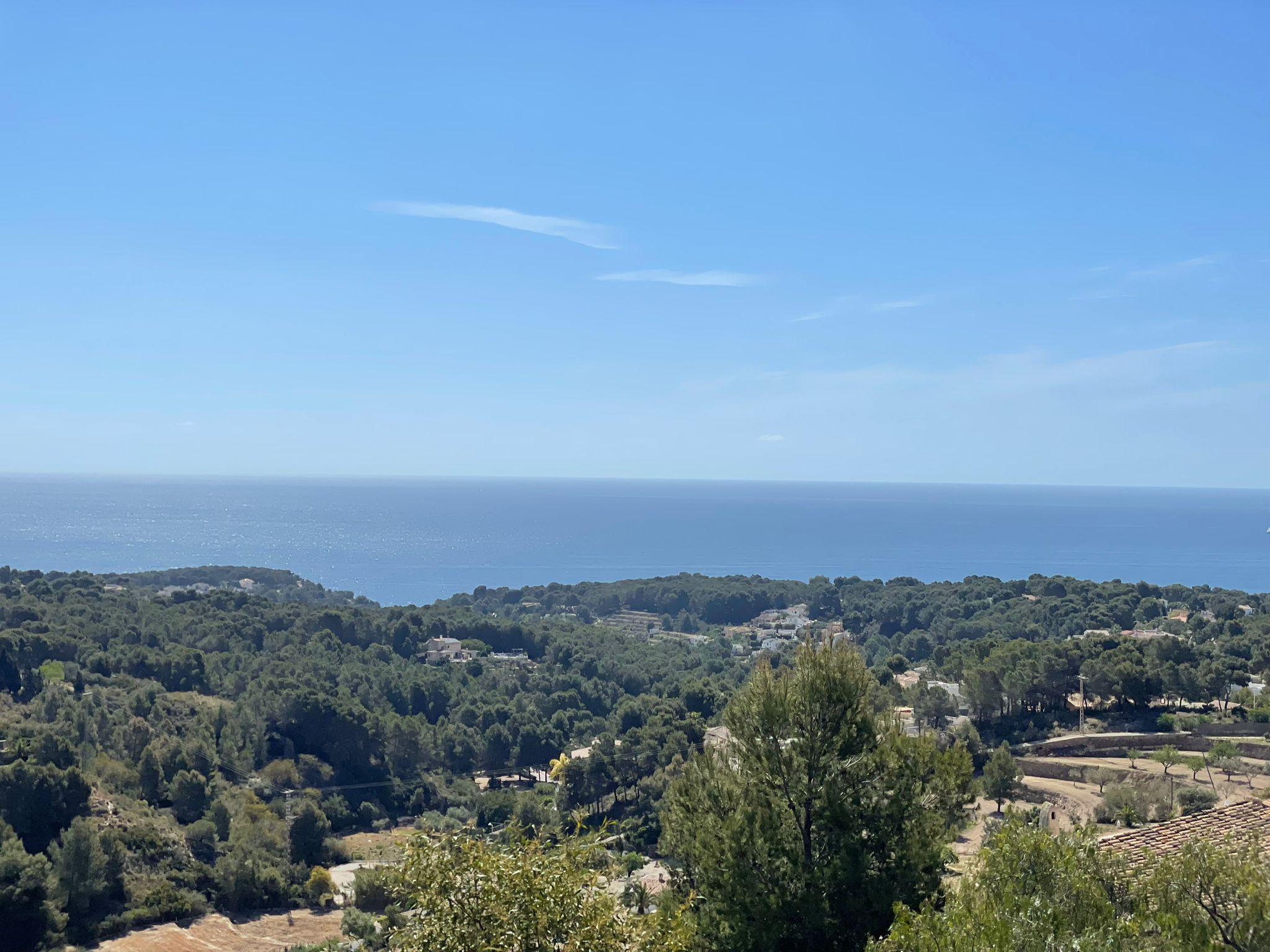 Panoramic elevated view from the villa overlooking the Mediterranean Sea and the lush green pine forests of the Benissa coastline.