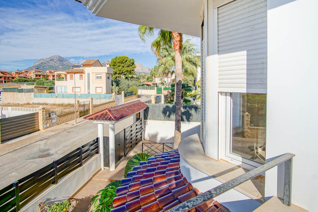 Elevated view from the upper terrace showing the gated entrance, terracotta roof details, and clear views of the surrounding mountains and neighborhood.