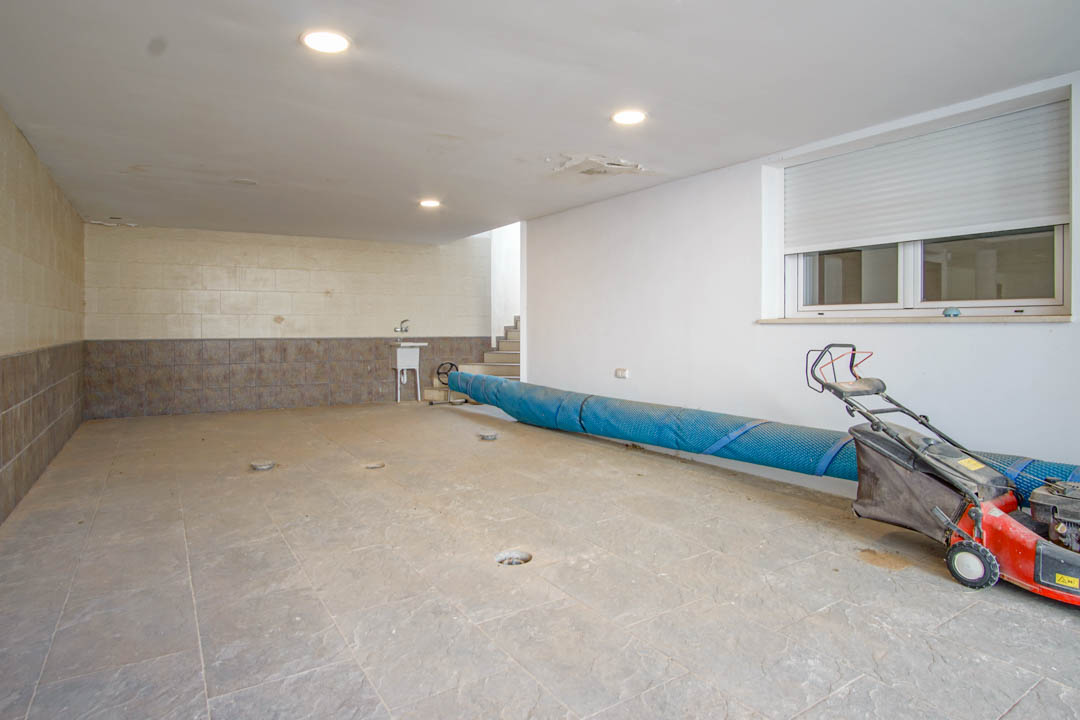 Spacious garage featuring ceramic tile flooring, recessed ceiling lights, and a utility sink. The area provides direct indoor access and ample storage for equipment.