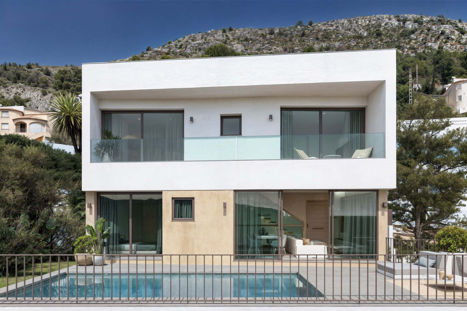 Modern two-story facade featuring a private swimming pool, floor-to-ceiling glass doors, and upper-level terraces with glass railings overlooking the valley.